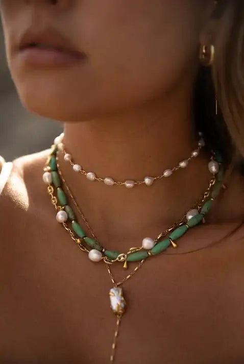 Stylish women's jewelry featuring layered necklaces with pearls and green accents, perfect for any occasion.